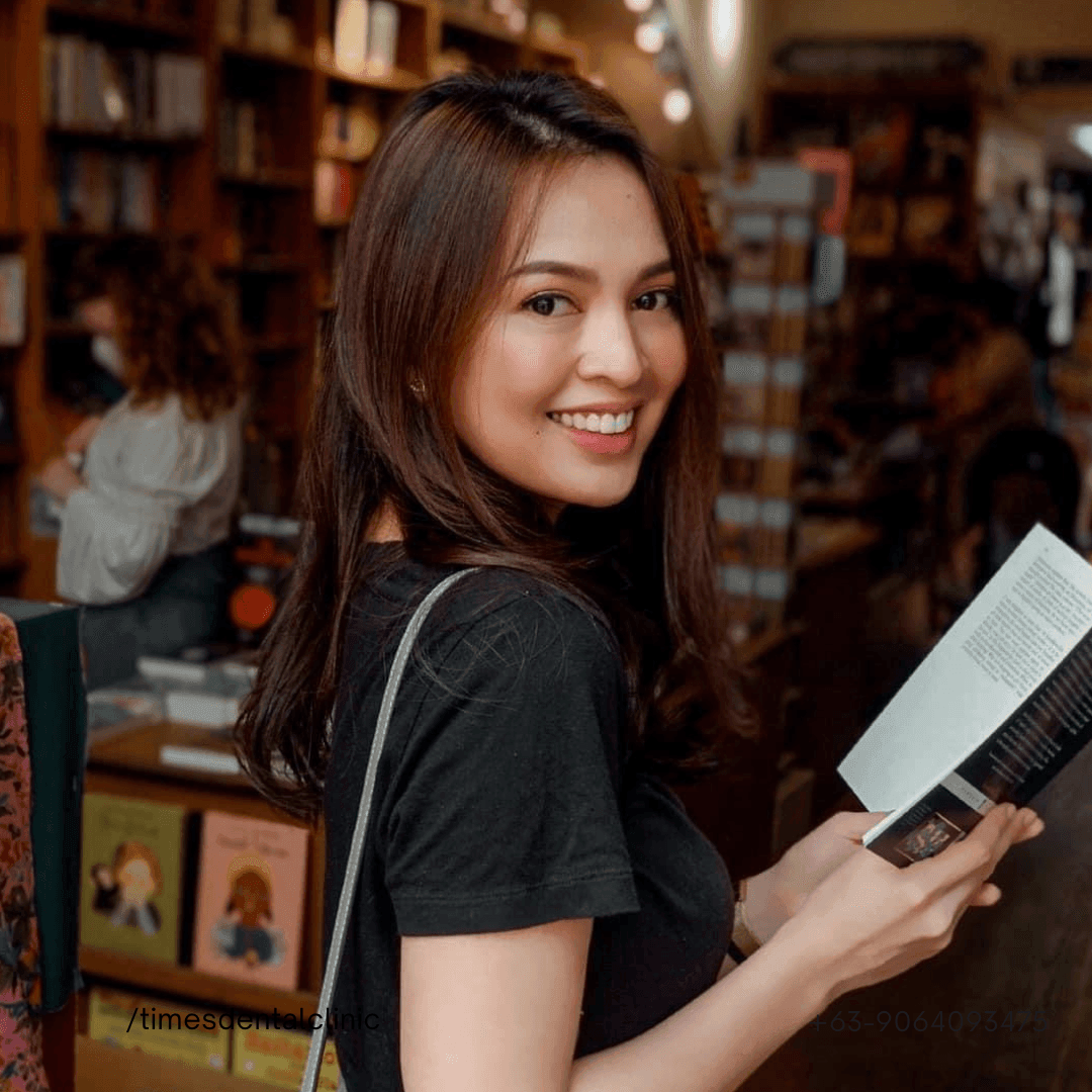 Person in a bookstore reading a book, with shelves of books and another person in the background.