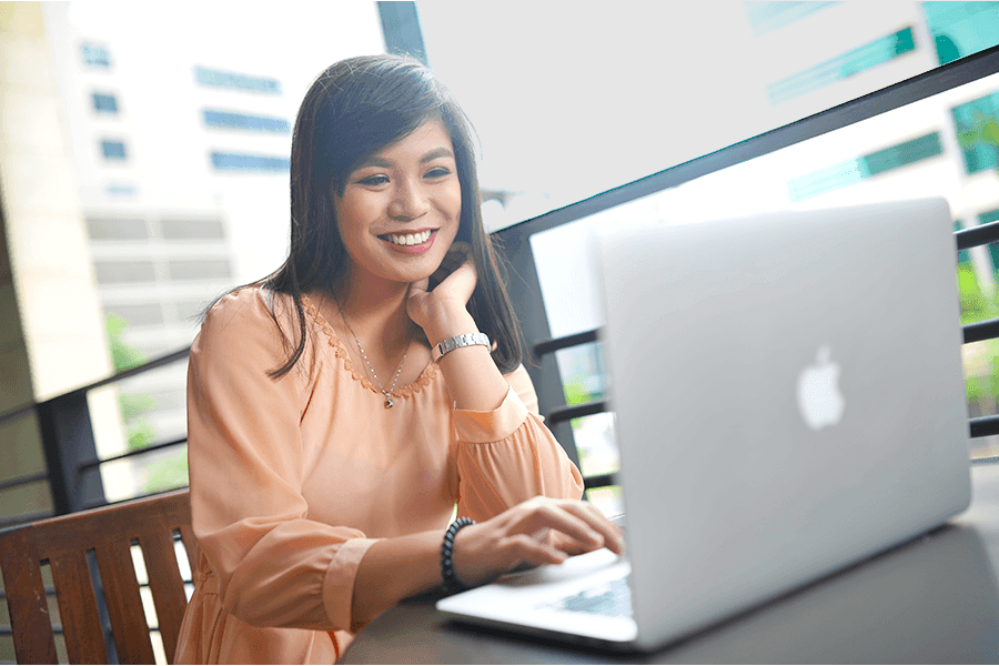 Person sitting at an outdoor table using a laptop with a cityscape background.